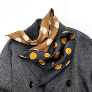 Luxury silk bandana scarves draped on gray coat - black with gold polka dots and ochre with cream polka dots, hand-rolled 53cm silk accessory