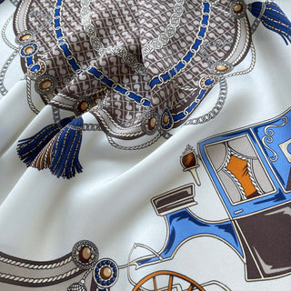 Luxury silk scarf featuring baroque equestrian design with blue tassels, intricate chain patterns, and carriage motifs on cream background