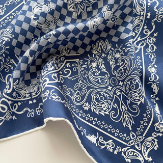Luxury silk bandana in steel Blue with white baroque pattern and checkerboard design, featuring hand-rolled edges and elegant draping