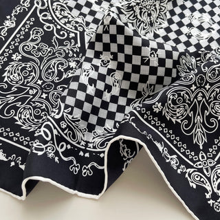Black and white silk scarf with baroque and checkerboard pattern featuring hand-rolled edges, displaying luxurious twill texture and intricate design