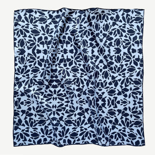 Square silk scarf with navy blue floral pattern on light blue background, featuring hand-rolled edges and elegant 65cm design