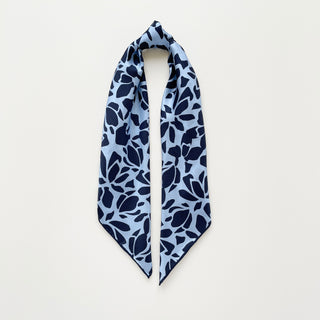 Blue Melody silk scarf with navy floral pattern on light blue background, folded to show square shape and hand-rolled edges.