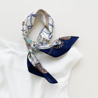 Turquoise & Navy Baroque Bridle silk bandana styled in a knot, featuring intricate equestrian design with decorative chains and ornamental patterns on white fabric.