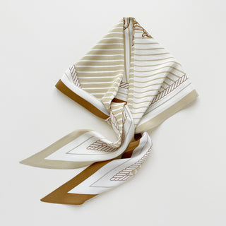 Elegantly folded silk scarf featuring beige and white stripe pattern with brown border and decorative rope monogram details on cream background