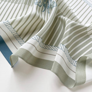 Luxurious silk scarf in cream and sage green with nautical rope pattern, featuring delicate stripes and blue decorative monogram accents