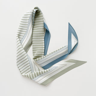 Luxury long silk scarf in sage green and beige with striped pattern and blue accents, elegantly draped to showcase its flowing design