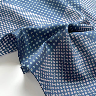 Blue silk scarf with repeating four-leaf clover pattern, showcasing luxurious sheen and hand-rolled edges of the men's neckerchief