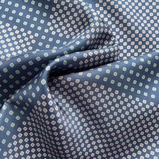 Navy blue silk scarf with repeating four-leaf clover pattern in white and subtle colored accents, showing luxurious fabric texture and folds