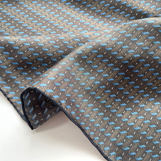 Charcoal grey silk neckerchief with light blue geometric pattern, featuring hand-rolled edges and luxurious twill texture