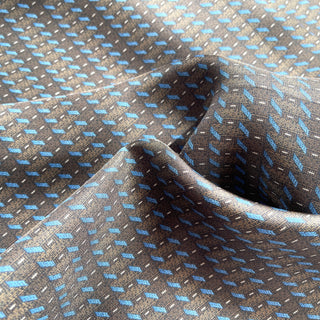 Close-up of charcoal grey silk neckerchief with light blue geometric line pattern showing luxurious fabric texture and subtle sheen