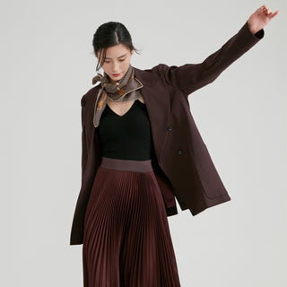 Black and beige houndstooth silk scarf styled as a neck accessory with a brown blazer, black top, and burgundy pleated skirt against neutral background