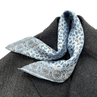 Sky blue silk neckerchief with classic paisley pattern and ornate border displayed on dark gray coat, showcasing elegant hand-rolled edges