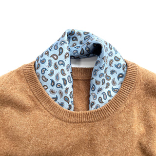 Light blue silk neckerchief with navy and brown paisley pattern elegantly styled with camel-colored sweater, showcasing refined men's accessory