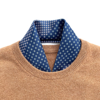 Blue silk neckerchief with white four-leaf clover pattern elegantly styled inside the collar of a camel-colored sweater