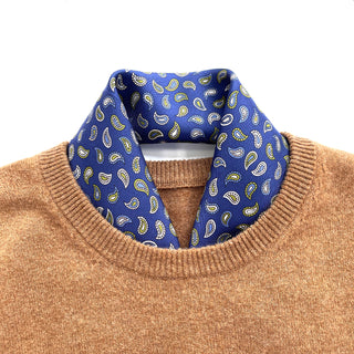 Blue silk neckerchief with yellow paisley pattern styled with a camel sweater, showing the elegant hand-rolled edges and luxurious twill texture.