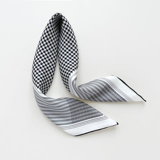 Elegant silk scarf with black and white houndstooth pattern transitioning to gray and white stripes, displayed in a flowing arrangement on white background.