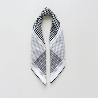 Square silk scarf with black and white houndstooth pattern, featuring striped borders and plaid corner designs on a luxurious white background with hand-rolled edges.
