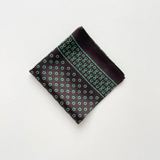 Folded silk scarf in brown with green horseshoe print pattern, featuring decorative border design on luxurious satin fabric