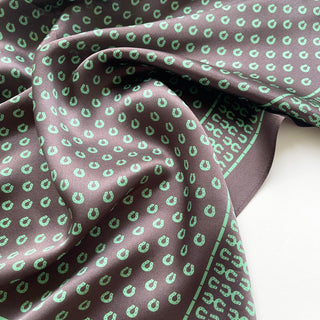 Brown silk scarf with green horseshoe pattern, showcasing the luxurious sheen and fluid drape of 100% silk satin fabric