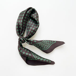 Silk scarf in brown with green horseshoe pattern, elegantly tied to showcase the lustrous fabric and classic print design