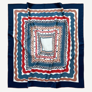 Square silk scarf with concentric wavy patterns in navy blue, red, and earthy tones, featuring hand-rolled edges and lustrous twill fabric