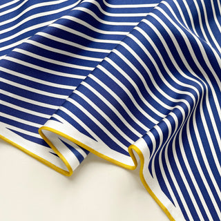 Luxurious silk triangle scarf with navy and white stripes, featuring elegant yellow hand-rolled edges, displayed to show smooth fabric texture