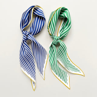 Two triangle silk bandana scarves with classic stripe patterns - one in deep blue and one in rich green, both featuring gold trim and hand-rolled edges