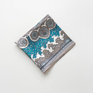 Folded silk bandana scarf featuring turquoise blue, white and taupe baroque pattern with ornate medallions and decorative border