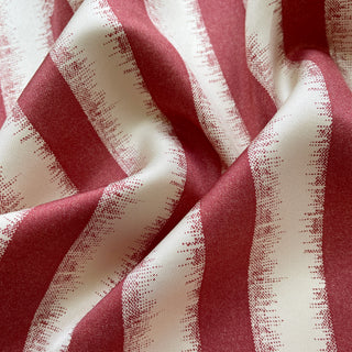 Close-up of luxury sand-washed silk scarf with grapefruit pink and cream stripes, showing soft texture and fluid drape of twill fabric