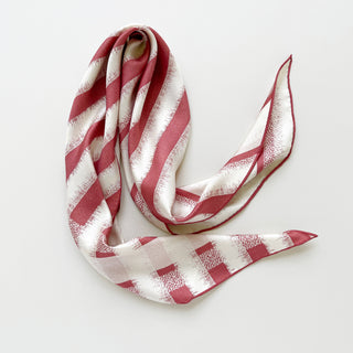 Luxury triangle silk scarf in grapefruit pink and cream stripes with textured pattern, showcasing soft drape and hand-rolled edges on white background.