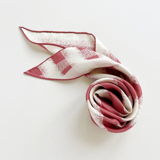 Triangle silk scarf with grapefruit pink and cream striped pattern, hand-rolled edges, and elegant sand-washed finish, displayed in a gentle swirl.