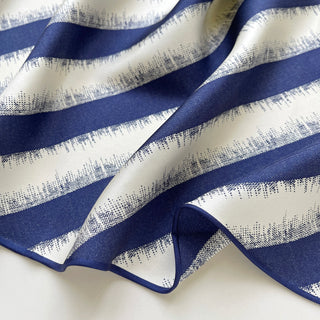 Luxurious silk scarf with elegant blue and cream stripes featuring textured dot pattern edges, showcasing sand-washed finish and soft drape