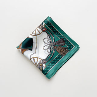 Folded luxury silk bandana scarf in teal green with baroque equestrian pattern featuring decorative tassels, ropes, and gold accents on white background