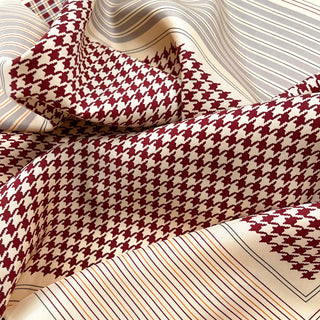 Luxurious silk scarf featuring deep red and cream houndstooth pattern with elegant striped border, showcasing the silky texture and hand-rolled edges