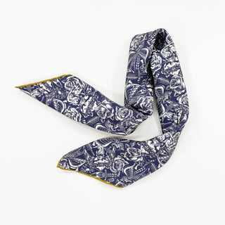Luxury ink blue silk scarf with white gothic rose pattern, featuring mustard yellow hand-rolled edges, displayed in an elegant S-shape on white background.