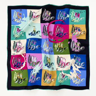 Square silk scarf with colorful blocks in blue, pink, green, and yellow featuring artistic snake motifs and scattered letters, bordered by black and teal trim