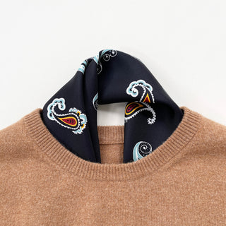 Black silk neckerchief with colorful paisley pattern styled with camel sweater, showing intricate design with teal, red, and yellow accents