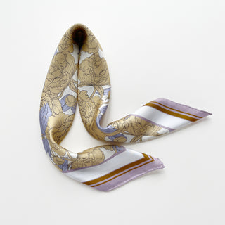 Luxury silk scarf featuring light yellow peonies print on white background with lilac and ochre border, showing delicate hand-rolled edges, elegantly displayed