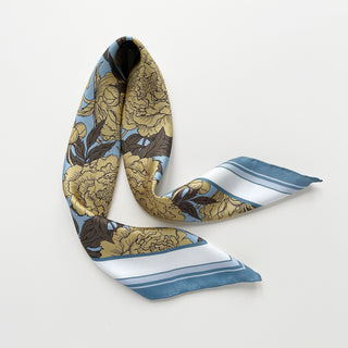 Luxury silk scarf featuring light yellow peonies print on light blue background with dusty blue border, showing delicate hand-rolled edges, elegantly displayed