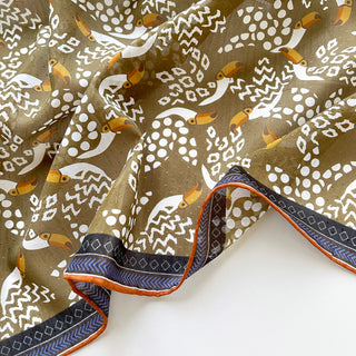 Organic cotton-silk scarf in mustard ochre with toucan print and understated jacquard, featuring contrast border and hand-rolled edges