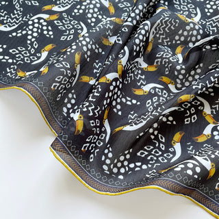 Organic cotton-silk scarf in black with toucan print and understated jacquard texture, featuring contrast border