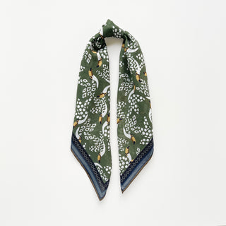 Organic cotton-silk scarf in green with toucan print and understated jacquard texture, elegantly draped on a white board