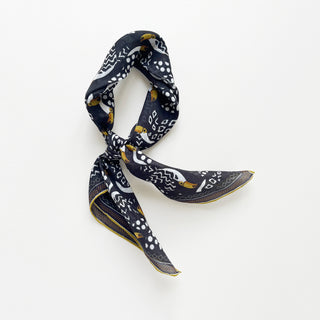 Organic cotton-silk scarf in black with toucan print and understated jacquard texture, featuring contrast border, elegantly tied in a loose knot