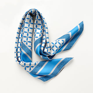 90x90cm silk scarf with geometric blue petal print and striped border on a light grey base, hand-rolled edges, made of double-sided printed silk twill.