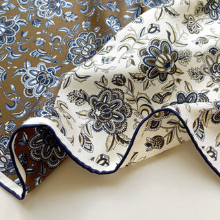 Detailed shot of men’s silk scarf edge, showing navy hand-rolled finish, brown and cream floral pattern on premium silk twill.