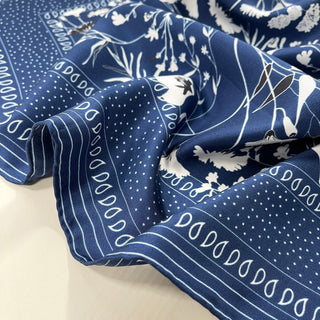 Blue Kyoto Blooms silk scarf with elegant white floral pattern and decorative border featuring dots and teardrop designs, showcasing luxurious twill texture