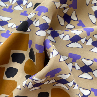 Close-up of 65cm unisex silk scarf with abstract geo print in mustard, black, beige, purple on matte silk twill