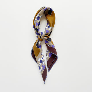 Unisex silk square scarf 65x65cm with geometric abstract pattern in earthy tones and hand-rolled edges on a light grey background.