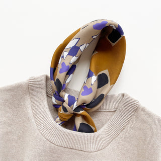 Unisex silk scarf 65x65cm with geometric abstract pattern in earthy tones elegantly tied and tucked into a beige sweater