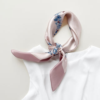 Blush pink silk bandana scarf with blue and burgundy leaf pattern, elegantly tied at neck against white clothing, showcasing silky sheen